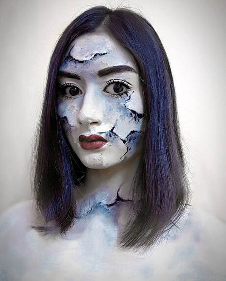 Photograph of a girl painted with white cracked skin