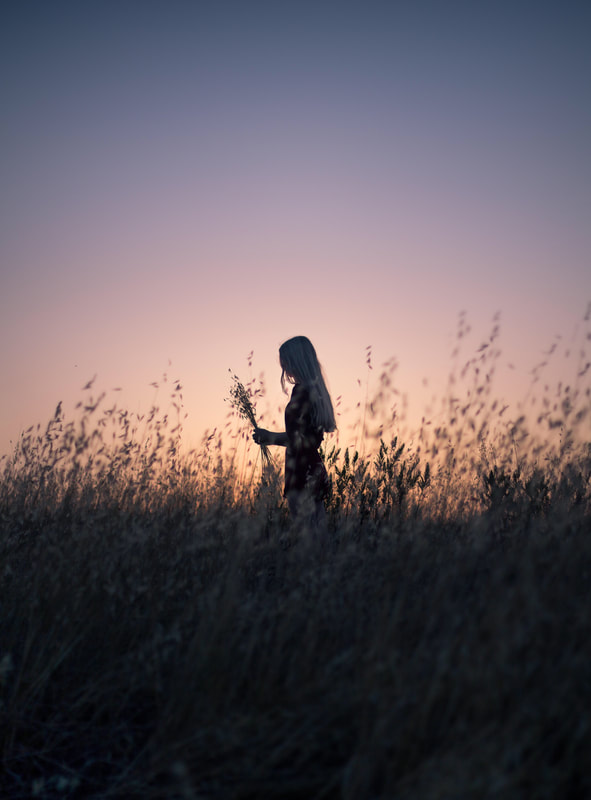 Photograph of a girl standing in a wheat field with a purple sky behind her